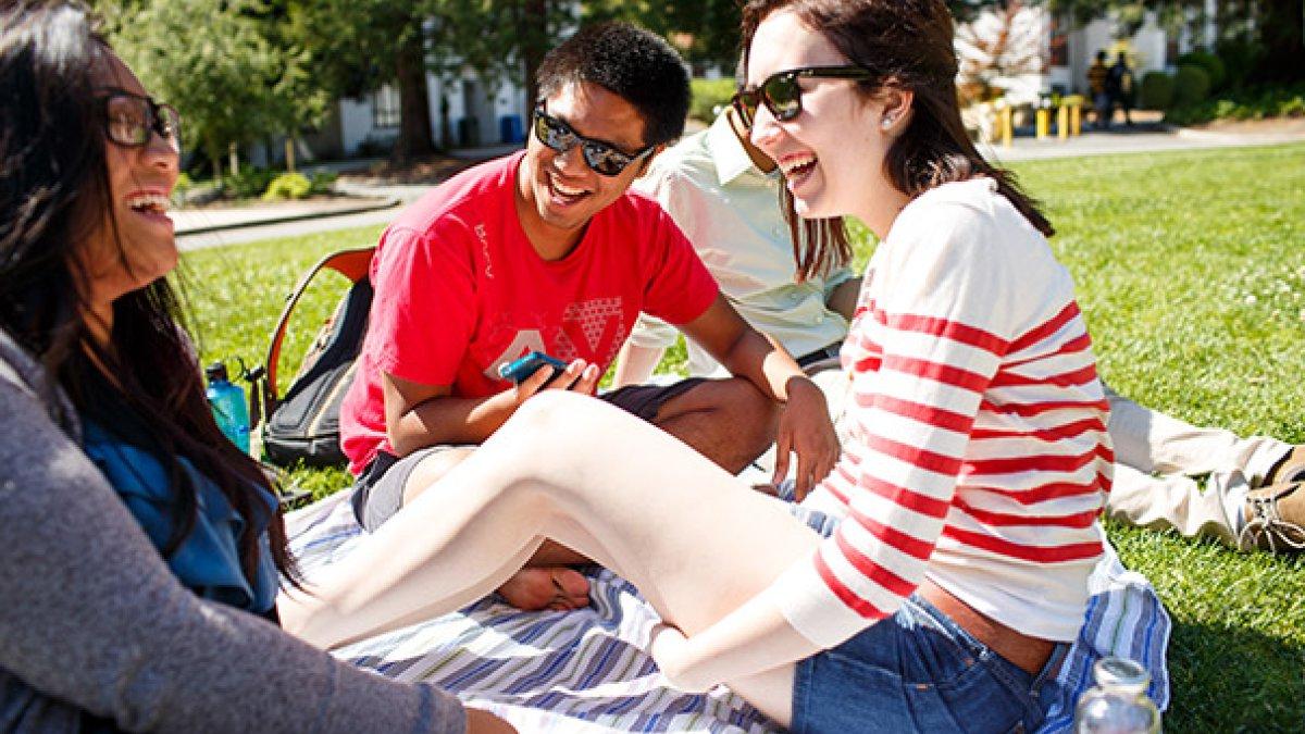 Students laughing sitting on the lawn